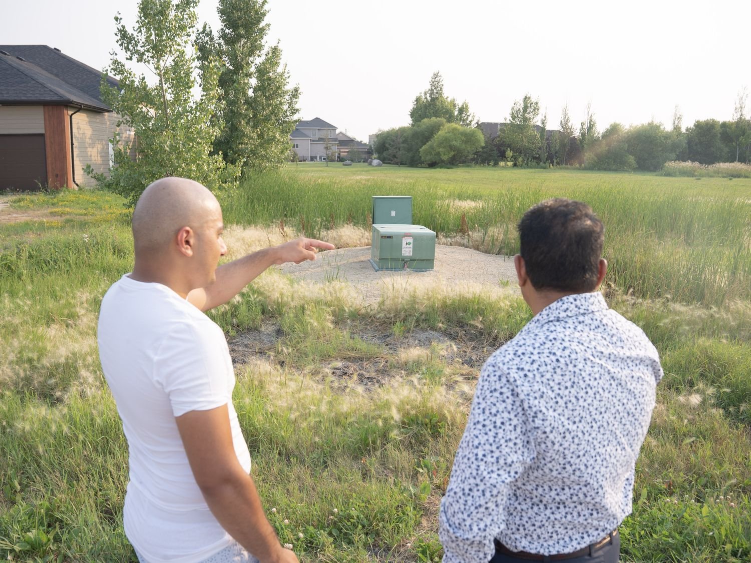 Jacky Maan and a resident looking at drainage infrastructure in a grassy field